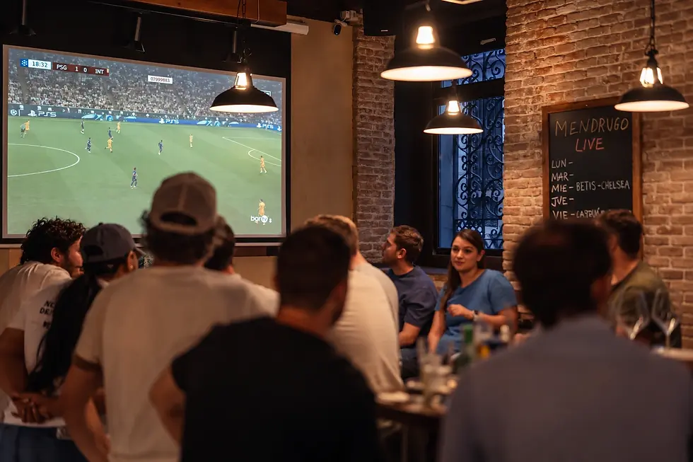Clientes viendo un partido de fútbol en la pantalla grande de Mendrugo.webp