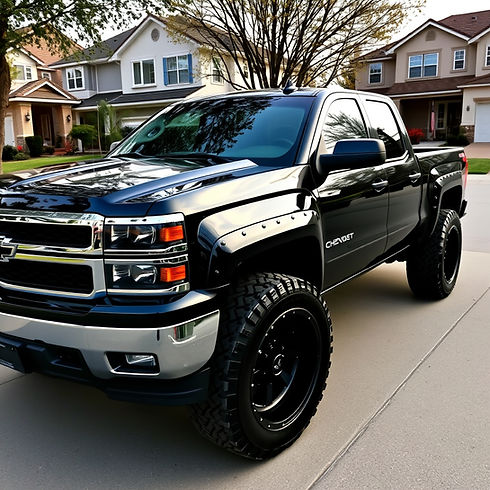 Black chevy truck with big heavy 33 inch tires and black rims; dark tinted window in a rea