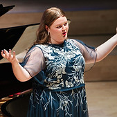 Ellie Forrester with arms raised in a sparkly dress mid performance.