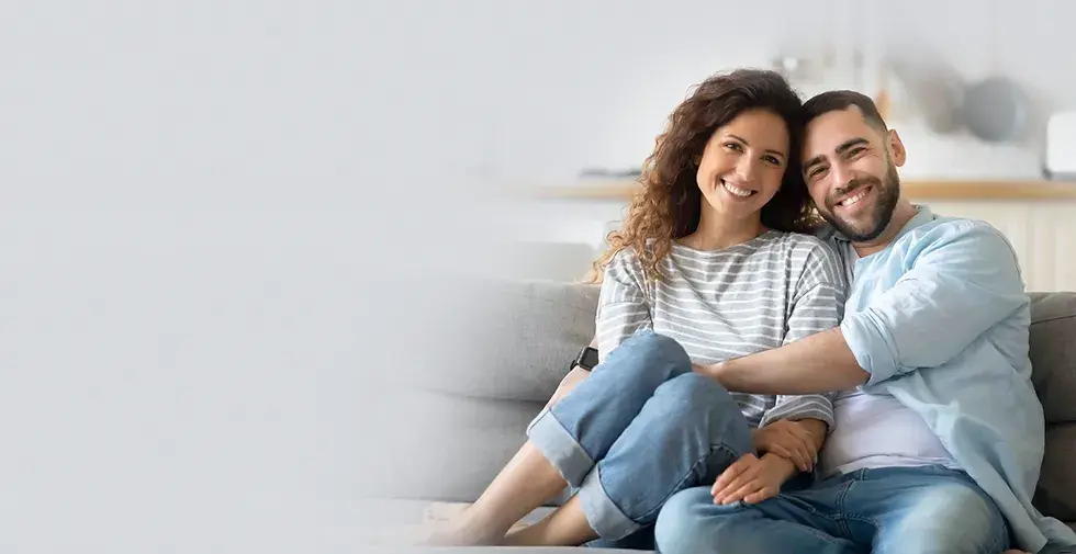 Happy couple sitting together on a couch and smiling, representing emotional well-being, healthy relationships, and improved mental wellness.