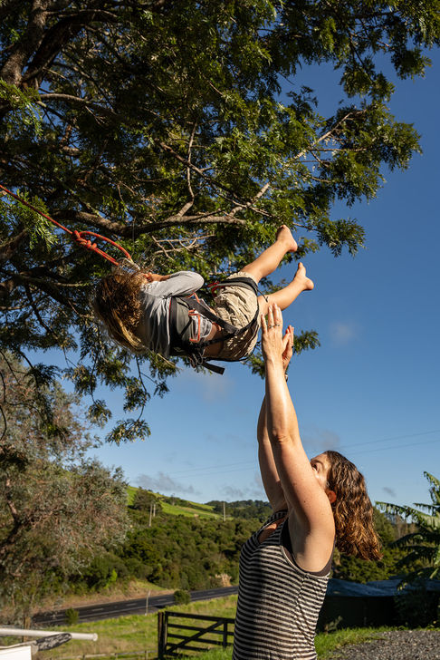 A mom pushes her kid in a rope swing