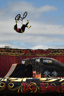 A skill bike mid flip with a kid clapping from the stands