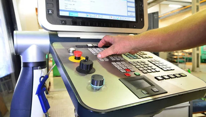 A technician operating a CNC control panel to manage industrial processes with accuracy, highlighting the importance of interface control in load cell systems.