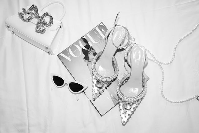 Elegant wedding shoes, statement necklaces, chic perfume bottles, and stylish wedding magazines, expertly captured by Loise Golding, wedding photographer, adding a touch of glamour and sophistication to every detail of the bride's special day.