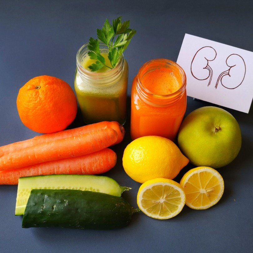 Natural Ayurvedic remedies for kidney health featuring fresh juices and vibrant produce like carrots, lemons, cucumbers, and more.