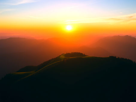 The sun sets over a silhouetted mountain range