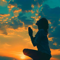 A person kneeling with hands clasped in prayer, set against a vibrant sunset sky filled with dramatic clouds.