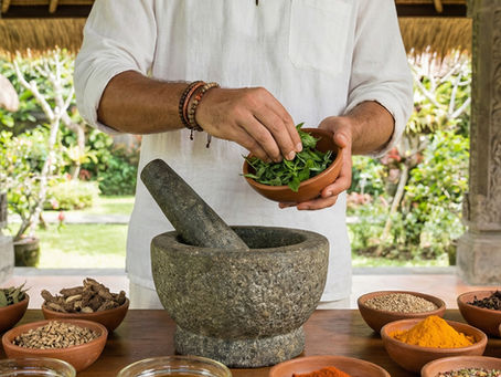 A person skillfully prepares Ayurvedic herbs using a traditional mortar and pestle