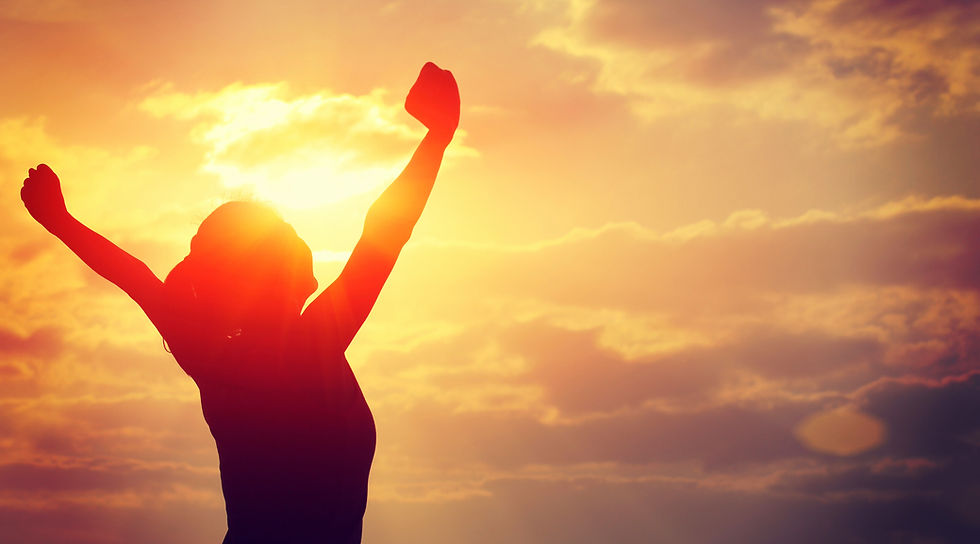 Silhouette of a person with raised arms against a vibrant orange sunset sky, conveying joy and triumph.