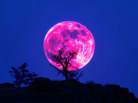 A luminous full moon rises over rugged mountain peaks,
