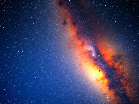 A vibrant orange and red nebula stretches across a starry night sky.