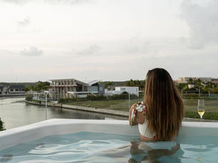 Mujer en piscina de terraza brindando con champán frente a la Marina Cap Cana, imagen de renta corta de ultralujo y estilo de vida premium.