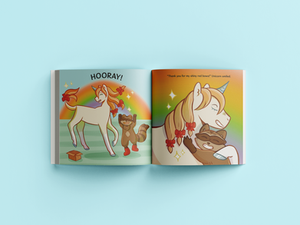 Open spread of a children's book. The illustrations portray Unicorn and Raccoon jumping in excitement at the red bows in Unicorn's mane. The background is rainbow colours. The two friends share a hug of joy.