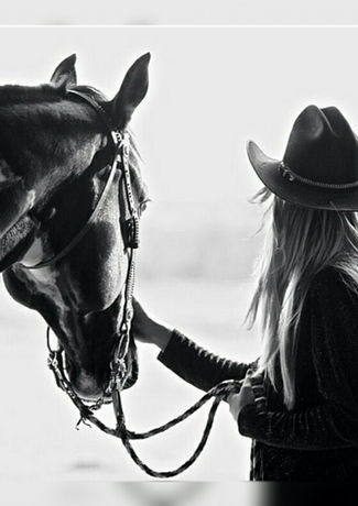 Cowgirl with horse. Woman leading horse with reins, black and white photo.