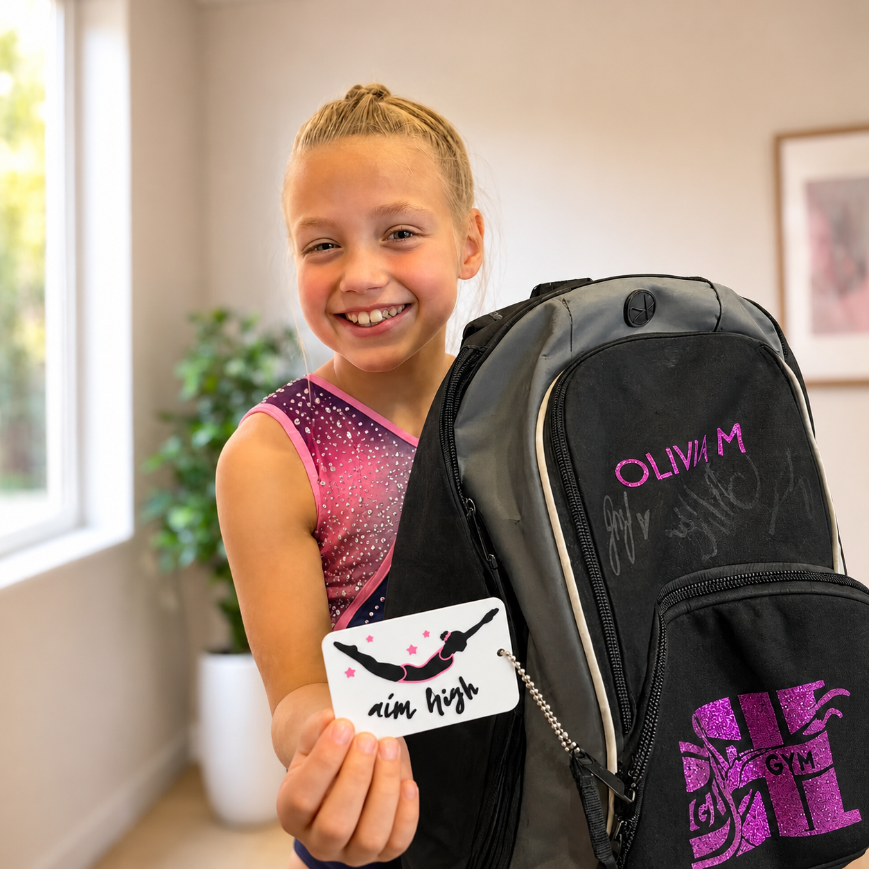 Gymnast showing Aim High Gymnastics bag tag on her bag