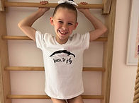 Smiling young girl on wall bars wearing a Born to Fly t-shirt