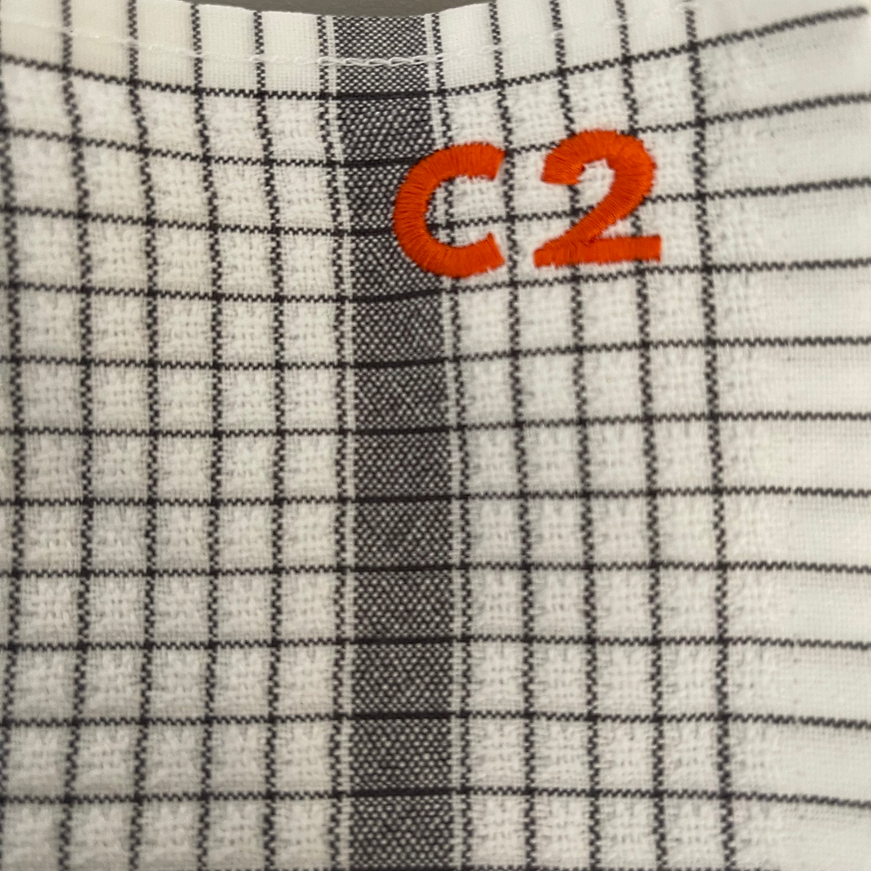 Tissu blanc à carreaux gris avec "C2" brodé en orange, broderie.
