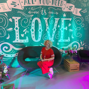 Andrea with her stall, with an 'All you need is love' backdrop