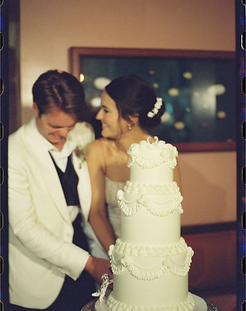New Orleans wedding couple cutting three tier vintage wedding cake with swans on top.