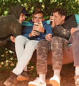 Three teens sitting together outdoors.