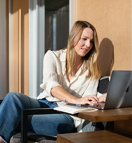 Adult woman sitting at a table using a laptop for virtual therapy.