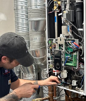 An ACE Plumbing and Heating employee conducts service on a boiler