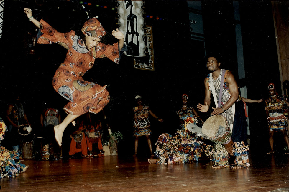 Olu Butterfly Woods leaps as King Salim Ajanku drums, at the Sankofa Center for Cultural Enrichment performance with Ibeji masks, c 2004-2005_photo by Armeta La Verne Gray