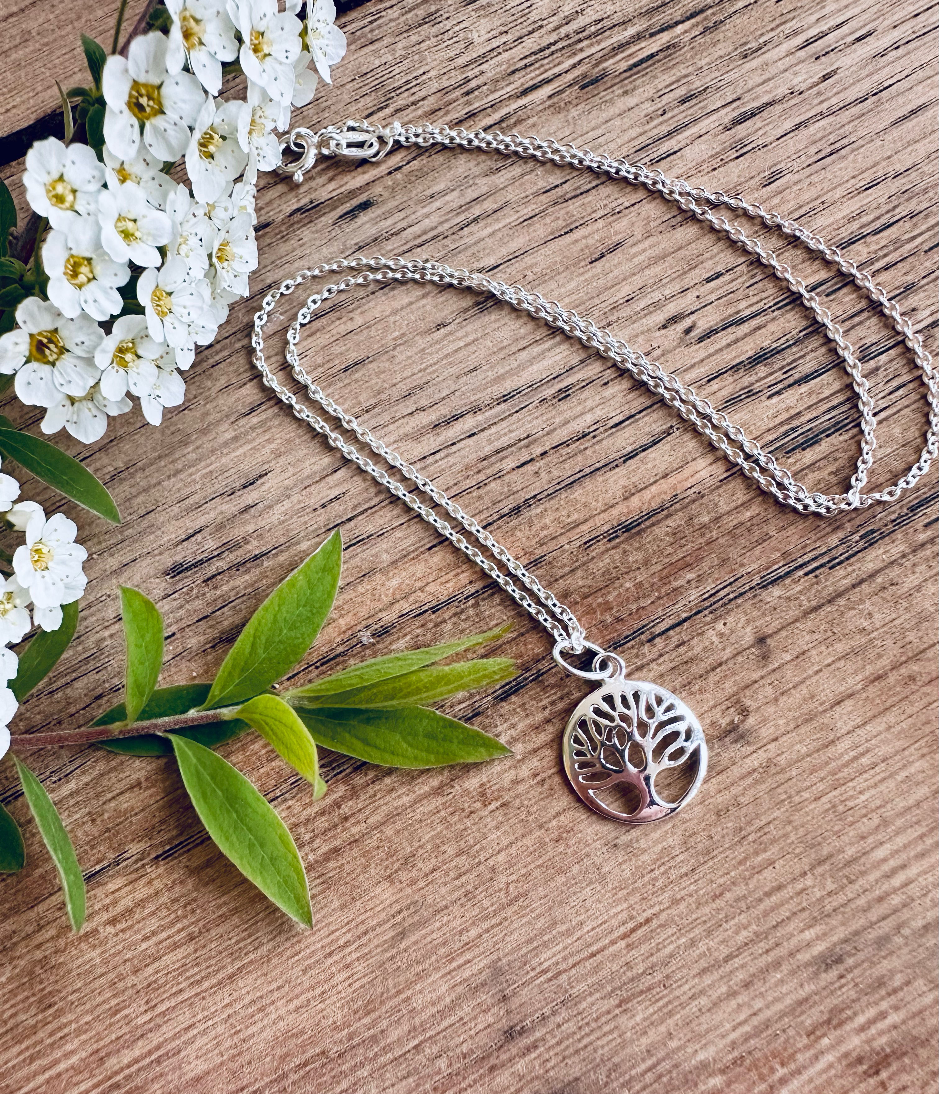 Tree of live round necklace displayed on wood with blossom flowers & leaves