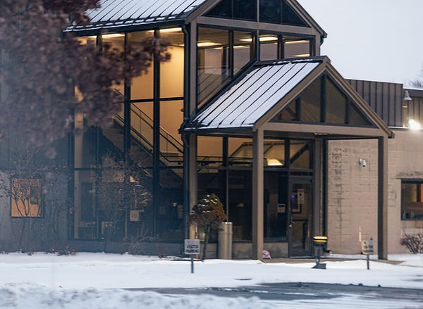 The front entrance to the Lippert building in Elkhart, at dusk, with warm light coming through the winows.