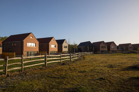 Evening / dusk view of dwellings with lighting highlighting bi‑fold doors and full-height glazing