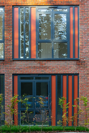 Three-storey Cecil Norris House in Shoreham‑by‑Sea, featuring a distinctive brick façade that transitions from deep red on st