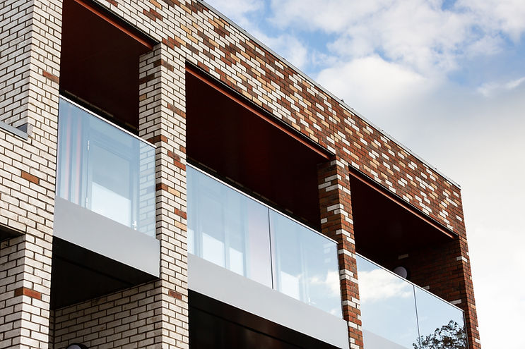 Three-storey Cecil Norris House in Shoreham‑by‑Sea, featuring a distinctive brick façade that transitions from deep red on st