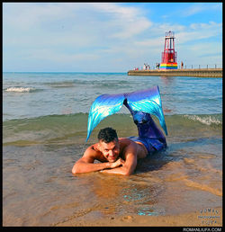 Merman with mermaid tail posing on a Chicago beach during Pride Month, Hollywood Beach