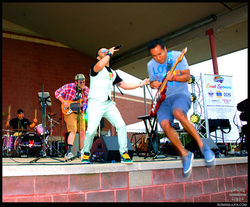 Charlie Foxtrot guitarist performing air guitar jump on stage at Lake County PrideFest