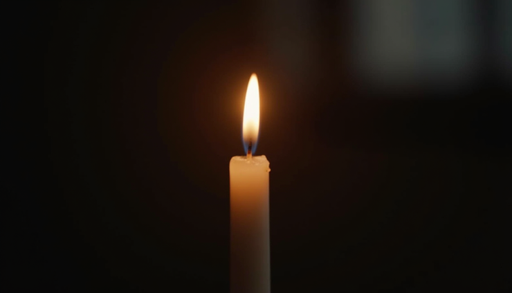 Eye-level view of a single candle flame glowing in darkness