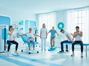 Imagem horizontal realista em 4:3 de cinco pacientes felizes de idades diferentes em uma clínica de fisioterapia moderna toda em tons de azul-claro e branco, recebendo tratamentos variados (respiratório, assoalho pélvico, equilíbrio neurológico, terapia manual nas costas e reabilitação de ombro), com fisioterapeuta sorridente ao centro. Paleta fria de branco e azul transmitindo calma, confiança e profissionalismo.