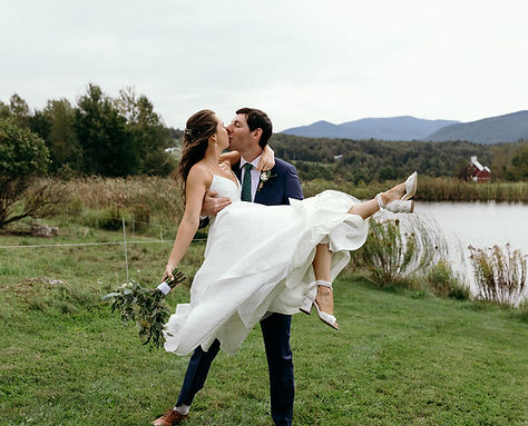 groom holding bride kissing by lakeshore