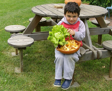 Un enfant tenant dans ses bras un panier contenant son buton du jardin autofertile