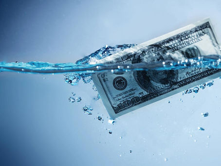 a hundred dollar bill half-submerged in water