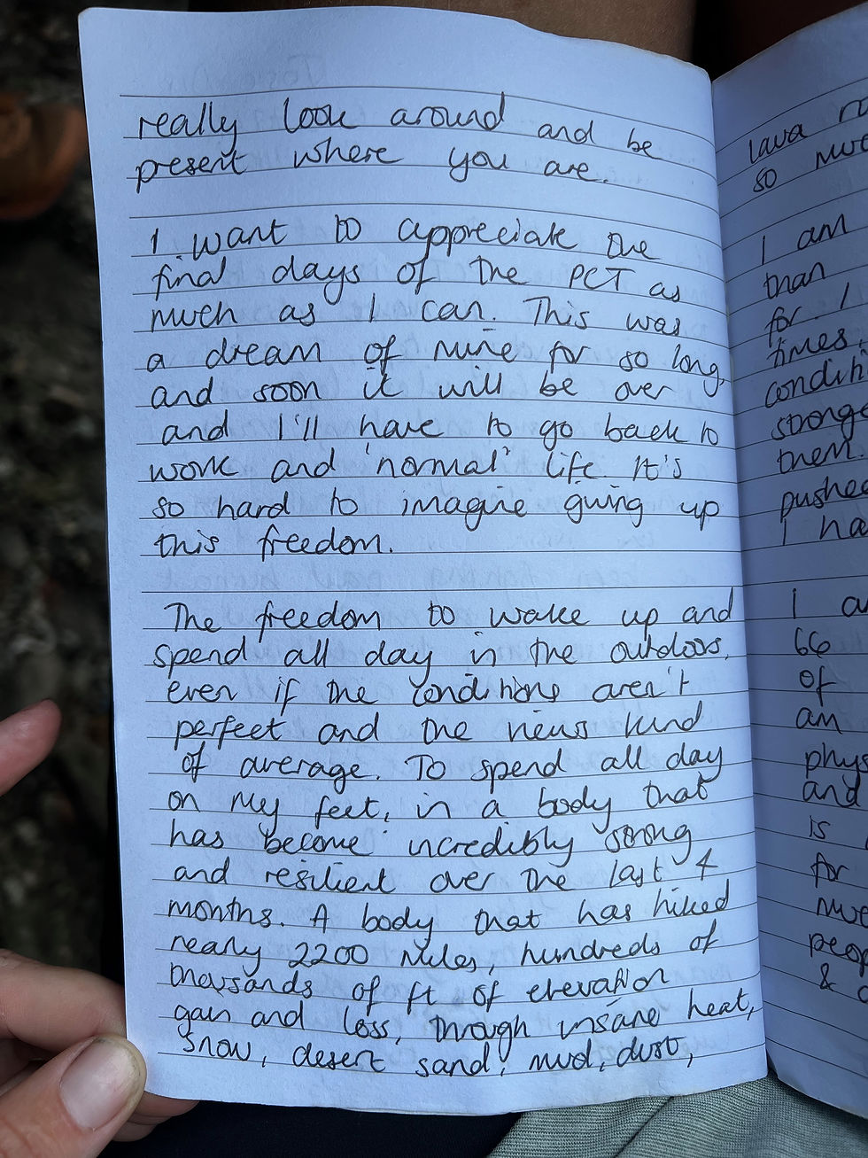 Close-up of a hand holding an open journal. The handwritten text reflects on appreciating the final days of a significant outdoor journey.