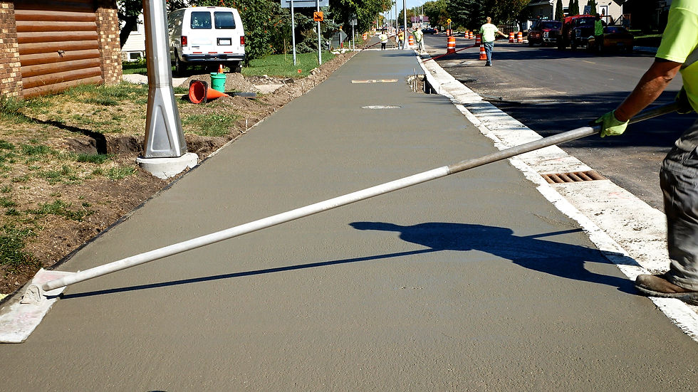 Workman finishes and smooths concrete surface on new sidewalk on sunny day.jpg