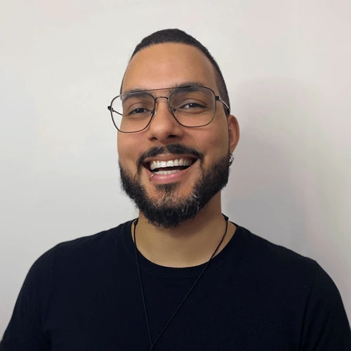 Foto de Felipe Augusto, identificado como Engenheiro de Software, sorrindo com cabelo curto, barba cheia e óculos. Ele veste uma camisa preta e está posicionado contra um fundo branco.