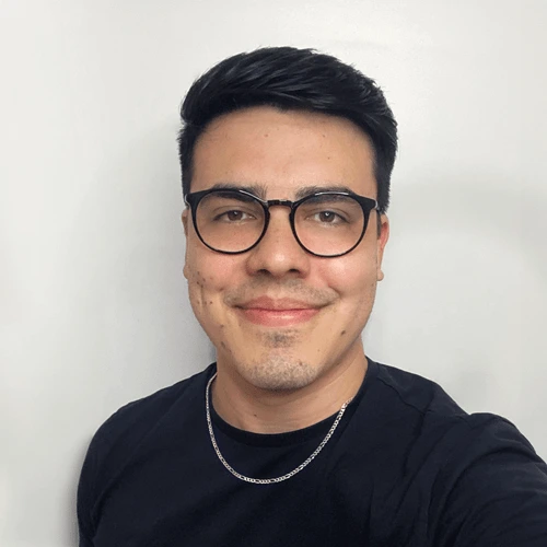Foto de Eduardo Gomes, psicólogo clínico, com expressão amigável, óculos e corrente discreta, em um fundo neutro, transmitindo profissionalismo e acessibilidade.