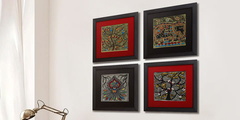 Four framed Saussurea Art madhubani painting pieces hanging on a white wall, decoratively arranged.
