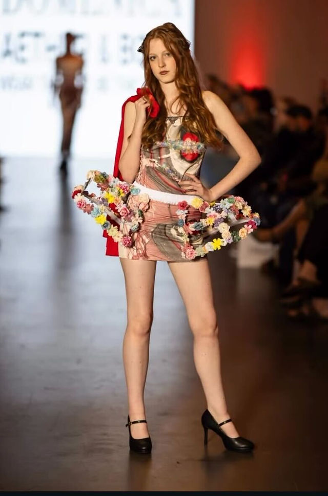 Model in an avant garde floral dress with long waves posing on the Charlotte Fashion Week runway.
