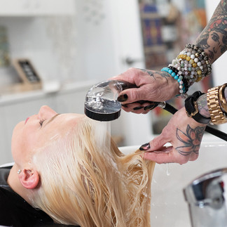 Stylist rinsing client’s hair with ECOHEADS filtered nozzle