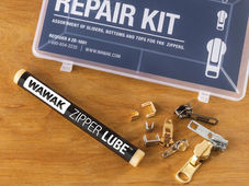 WAWAK zipper lubricant, zipper repair kit, and scattered metal zipper stops and sliders on a wood surface.