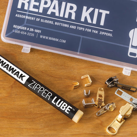 WAWAK zipper lubricant, zipper repair kit, and scattered metal zipper stops and sliders on a wood surface.