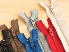 YKK #3 Nylon Coil Zippers in several colors on a wooden background