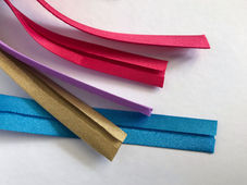Various colors of single-fold bias tape on a white background